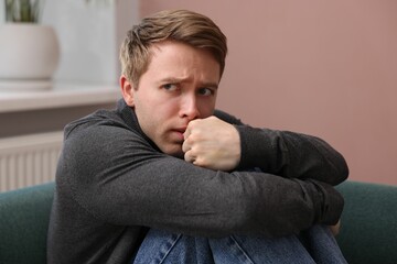 Man suffering from paranoia on sofa at home