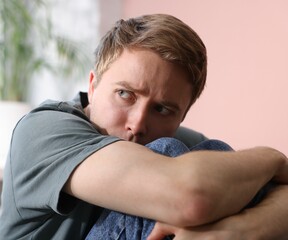 Scared man suffering from paranoia at home