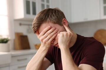 Young man suffering from paranoia in kitchen
