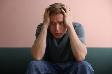 Man suffering from paranoia on sofa at home