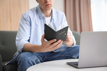 Man with passport near laptop at home, closeup