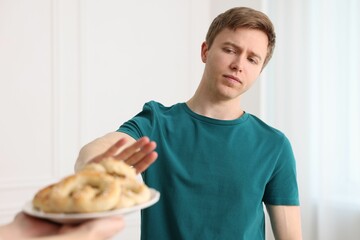 Gluten free diet. Man refusing from pastries indoors, selective focus