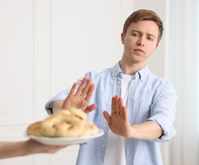 Gluten free diet. Man refusing from pastries indoors, selective focus