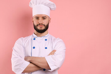 Portrait of confectioner in uniform with crossed arms on pink background