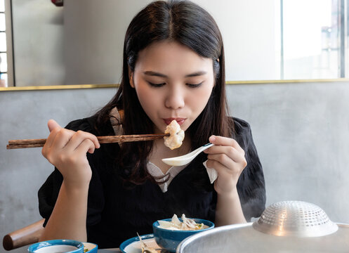 A Chinese woman is eating hot pot with Zhongshan crispy grass carp in Guangdong, China