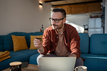 Man doing online shopping using credit card and laptop at home