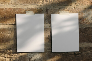 Two blank sheets of paper, greeting card templates taped to textured brick wall. Soft natural light...