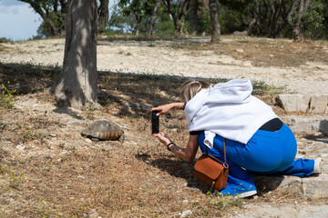 Young woman photographs a turtle in the wild