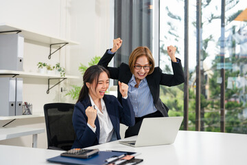 Overjoyed emotional businesswomen showing yes gesture, using laptop, celebrating success, excited...