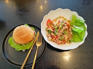 Spicy Instant Noodle Salad and Crispy Chicken Burger Served on Black Table