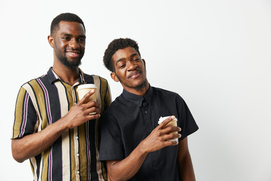 Two black men enjoying coffee together, smiling brightly in casual clothing. Capturing friendship and joy in a relaxed setting, ideal for lifestyle themes.