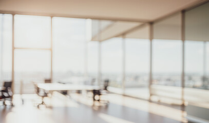 Blurred empty office room with large windows and a table with chairs.