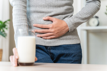 asian young woman having a stomachache, abdominal pain or digestive, hand in holding belly after...