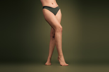 Portrait of a young woman showcasing her natural beauty in fitness wear against a khaki background