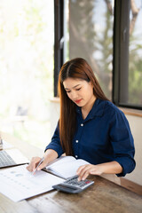 Woman holding pen pointing on paper using calculator for business financial accounting calculate...
