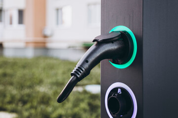 Electric car charging at plug in charging station in a public car park.