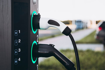 Electric car charging at plug in charging station in a public car park.