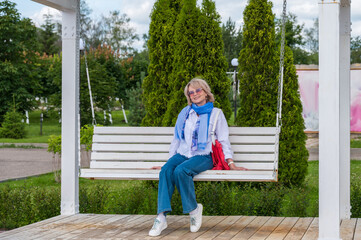 Woman is riding on a swing in summer park.