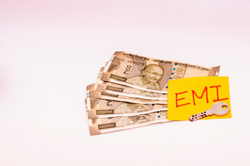 Conceptual image of Indian 500 rupee notes with EMI sticky note and a key symbolizing home loan...