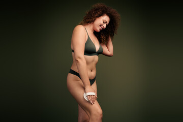 Confident woman with curly hair in stylish green lingerie celebrating body positivity and self...