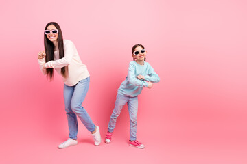 Mother and daughter bonding on a pink backdrop celebrating leisure and joy together