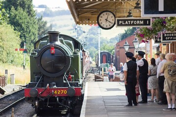 Steam train arriving at retro railway station platform, Midlands, UK