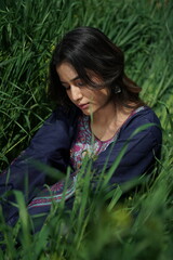 A Kashmiri girl in a traditional blue kurta stands amid spring’s wilderness — framed by blue...