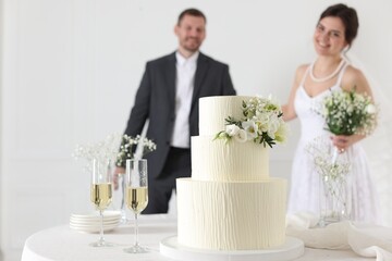 Happy married couple together indoors, focus on wedding cake on table