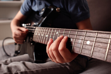  Young boy playing electric guitar at home, learning music and practicing concentration. The child appears focused and relaxed, suggesting a music practice or learning moment. Play music at home. 