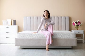 Woman on bed with orthopedic mattress at home