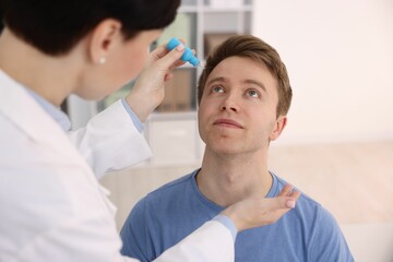 Ophthalmologist applying medical drops onto patient's eye in clinic, closeup