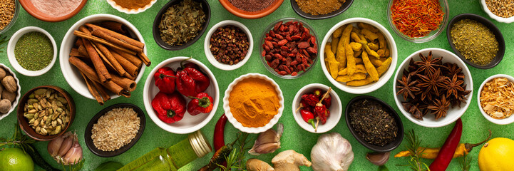A colorful assortment of fresh, fragrant spices and herbs displayed on a soft green background,...