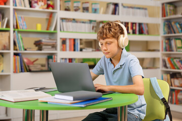 Student with laptop studying at table in library