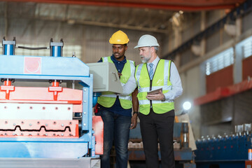 Workers discuss project details in industrial facility during daylight hours with safety gear on