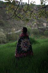 A young girl in an open field showcasing a beautifully handcrafted Kashmiri carpet, highlighting...