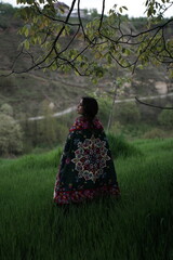 A young girl in an open field showcasing a beautifully handcrafted Kashmiri carpet, highlighting...
