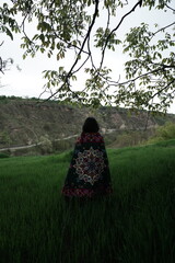 A young girl in an open field showcasing a beautifully handcrafted Kashmiri carpet, highlighting...