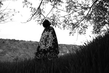 A young girl in an open field showcasing a beautifully handcrafted Kashmiri carpet, highlighting...