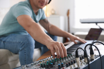 Man working with dj mixer and MIDI keyboard indoors, selective focus