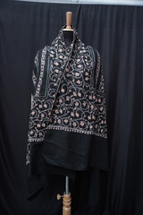 Elegant display of Kashmiri shawls draped on a mannequin, featuring intricate Sozni embroidery that...