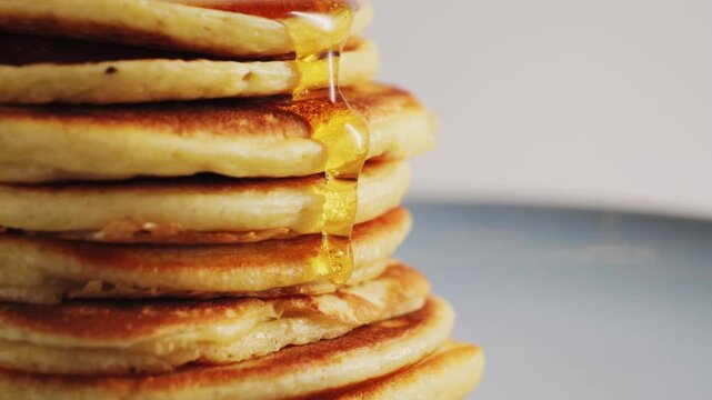 Close up pouring honey over stack of pancakes. Concept of sweet brunch. High quality 4k footage