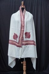Elegant display of Kashmiri shawls draped on a mannequin, featuring intricate Sozni embroidery that...