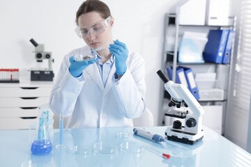 Scientist working with sample in Petri dish at table in laboratory
