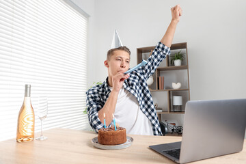 Happy man celebrating his birthday while having video call at desk indoors