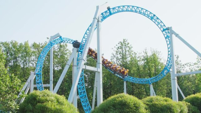 Roller coaster Ride against blue sky. Roller coaster in the amusement park. Cheerful entertainments in park of attractions