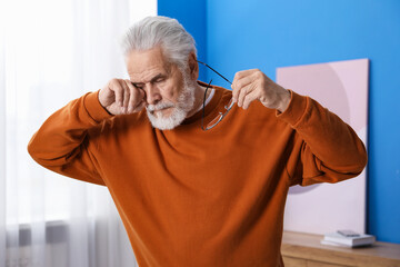Senior man with glasses suffering from eyestrain at home