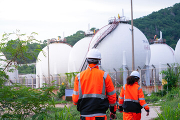 Two engineers in high-visibility safety gear and hard hats discuss project plans on a laptop in...