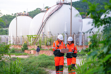 Two engineers in high-visibility safety gear and hard hats discuss project plans on a laptop in...