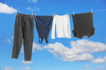 Different clothes drying on washing line against blue sky
