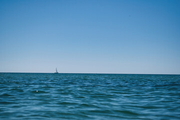 Obraz premium Segelboot am Horizont auf ruhigem Meer unter klarem Himmel